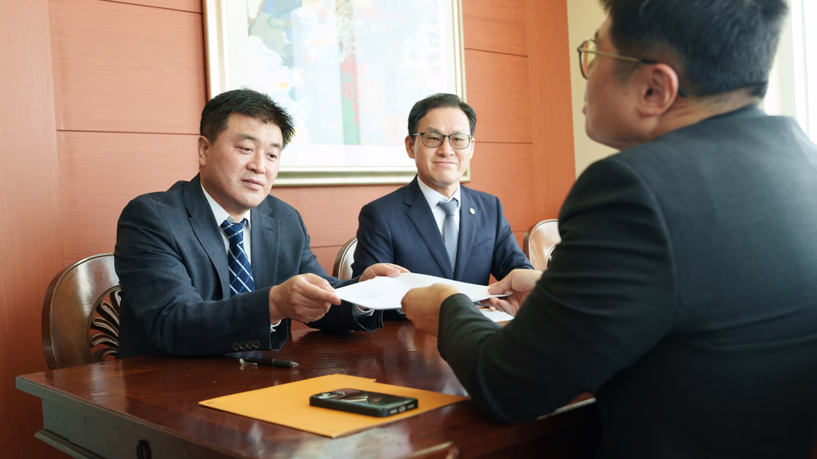 상담 테이블에서 서류를 주고받으며 대화하는 모습